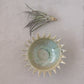 top view of the stoneware sunburst bowl next to grass on a light gray surface