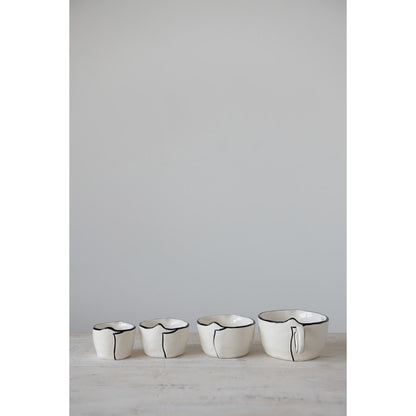 black and white measuring cups in a row on a countertop.