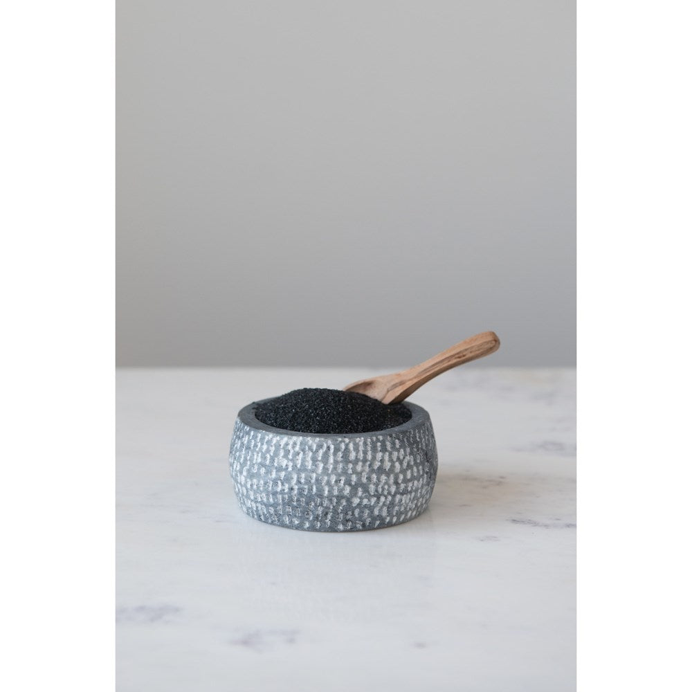 grey granite bowl filled with spice and a a wooden spoon set on a marble table.