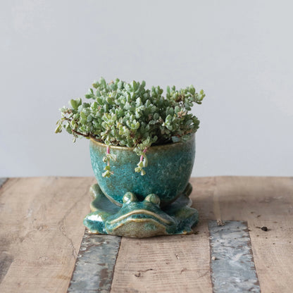 stoneware planter with frog base filled with succulents and displayed on a rustic wooden surface