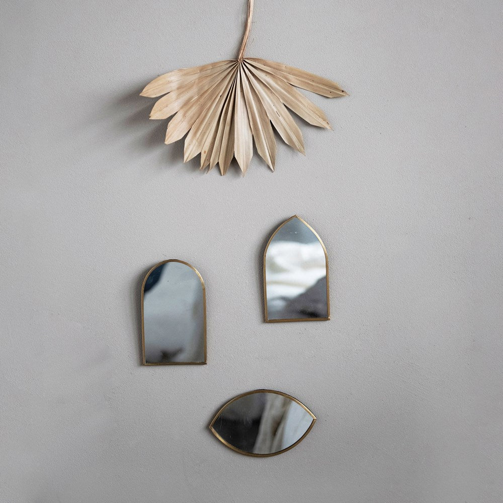 all three styles of metal framed wall mirrors displayed with a dried palm leaf on a gray background