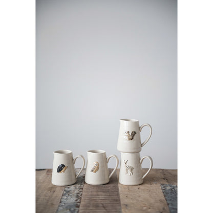 two creamer with forest animals stacked beside two other creamers on a rustic wooden table against a white background