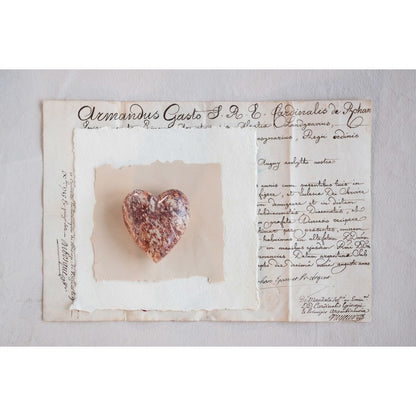 red and tan soapstone heart displayed on torn pages