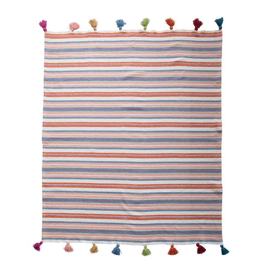 pink, orange, blue, and white striped blanket with a rainbow of end tassels laid flat on a white background.