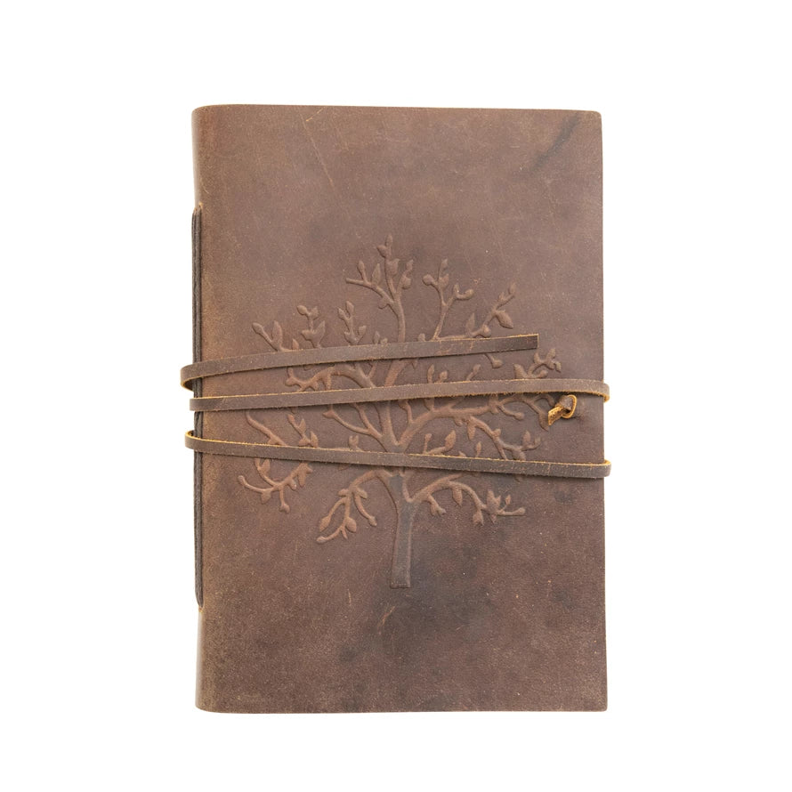 brown leather bound journal with an embossed tree on the front with a leather strap wound around it on a white background