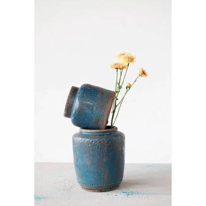 2 blue vases stacked with yellow flowers in the bottom vase.