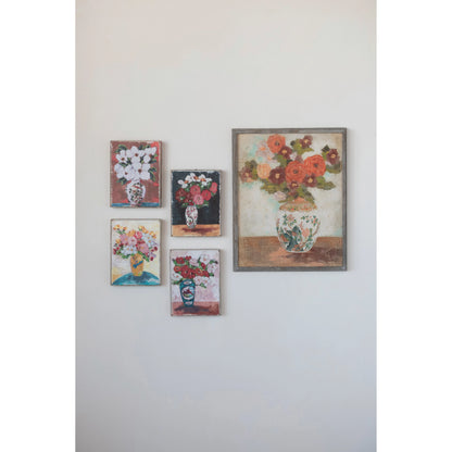 4 small floral prints and a 1 large framed floral print hung on a wall.