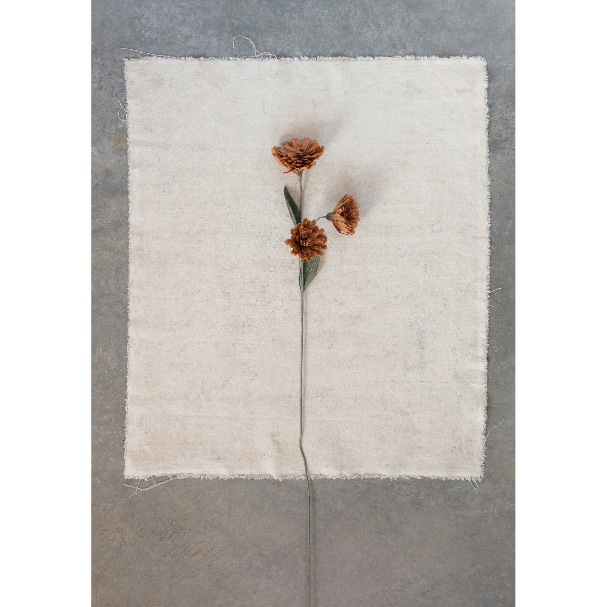 stem with 3 rusty colored mum flowers laying a piece of natural linen.