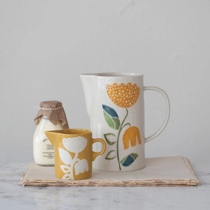 creamer set on a stack of papers with a larger pitcher and a jug of milk.