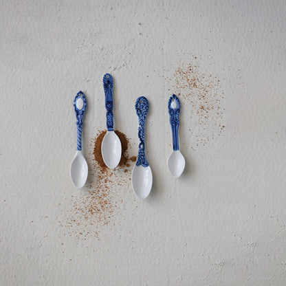 white ceramic spoons with blue handles on a grey background with scattered spices.