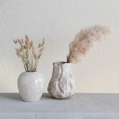 vase with plume in it set on a table with another vase filled with dried thistle stems.