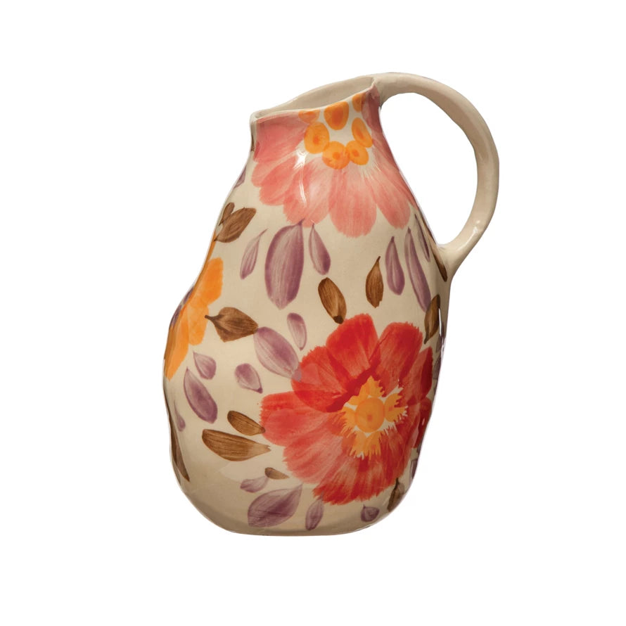 hand painted floral stoneware pitcher with pink, orange, yellow and purple flowers all over displayed against a white background