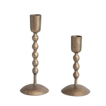 brass candle sticks with bead-like stems on a white background.