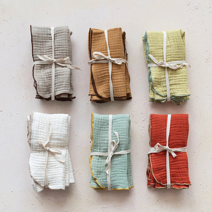 all six colors of contrasting stitched edge cloth napkins tied together and displayed on a white surface