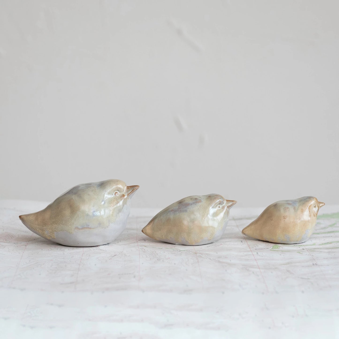 all three sizes of tan color stoneware birds displayed in a row on a white background