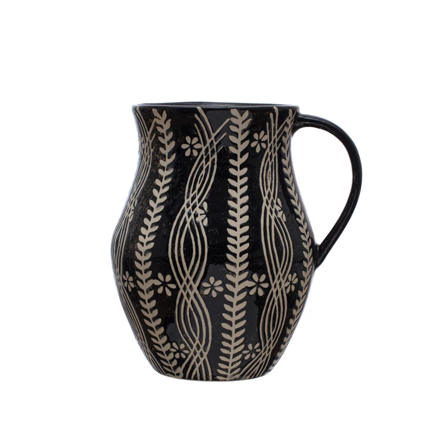 black and cream pitcher with floral and vine patterns on a white background.