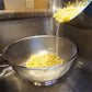 pasta being poured into colander in sink.