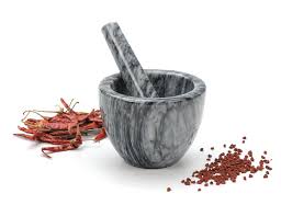 mortar with pestle in it and spices next to it.