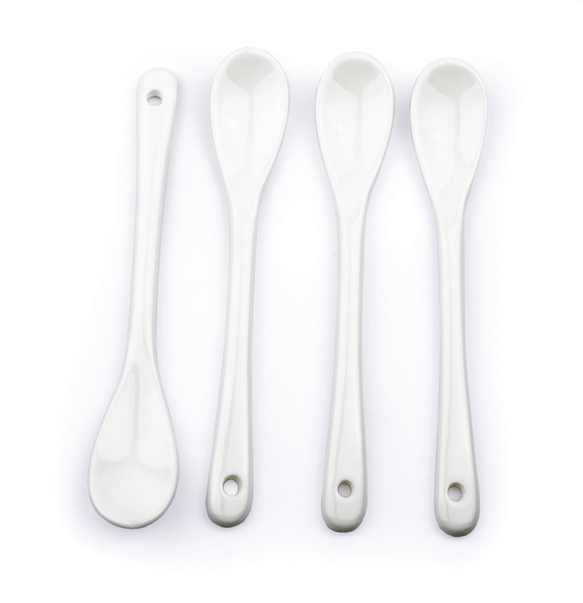 4 white ceramic spoons on white background.