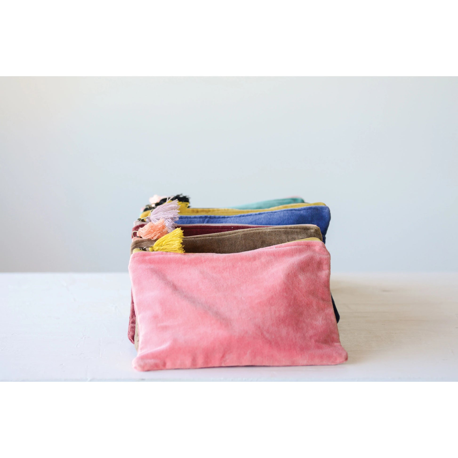 all six colors of velvet zip pouch with tassels displayed rowed up on a white background