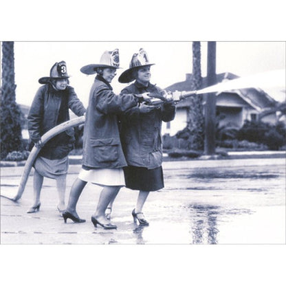 front of card is a photograph of women in heals and skirts pulling a spraying  fire hose 