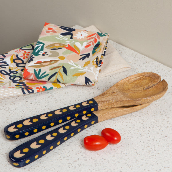 wooden salad servers on counter with towels and tomatoes.