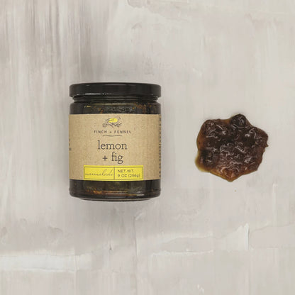 jar of lemon fig marmalade laying next to a dollop on a light colored surface