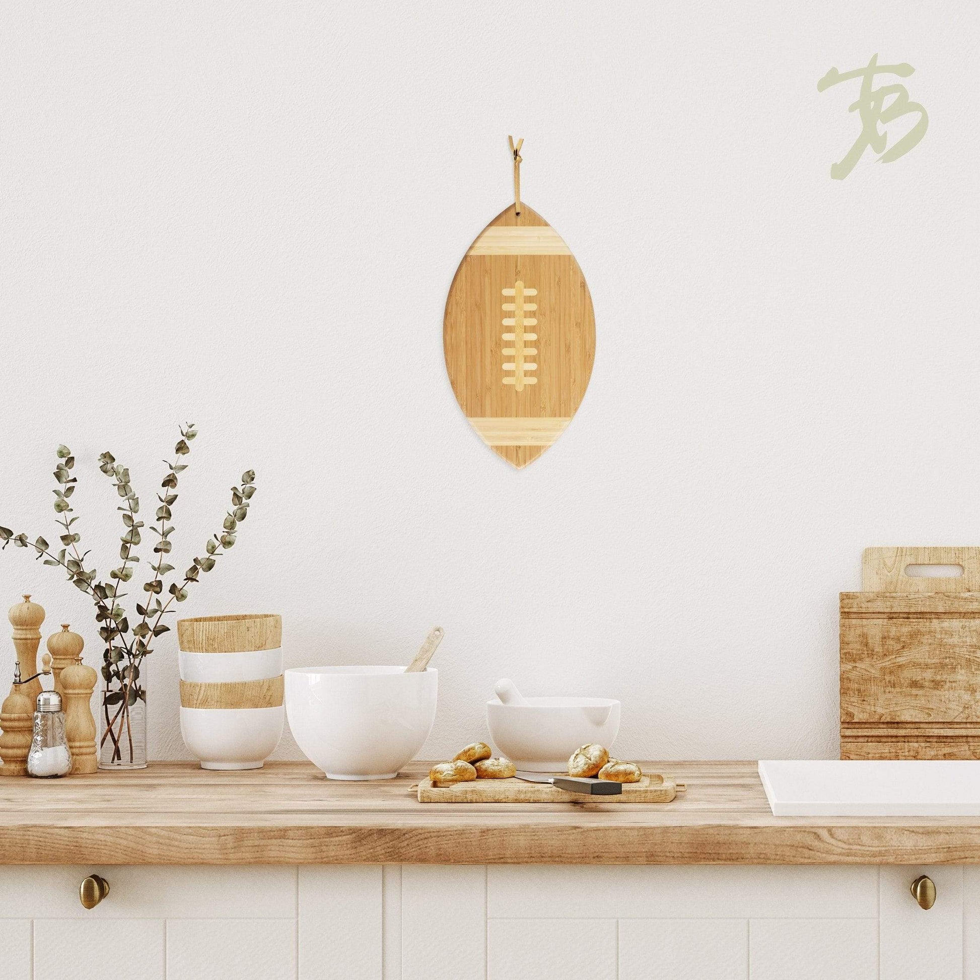 the football shaped serving and cutting board displayed hanging on a white wall in a kitchen
