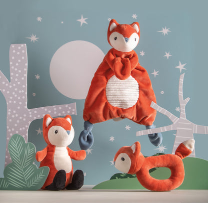 leika little fox lovey displayed next to the fox soft toy and fox rattle against a depiction of outdoors at night