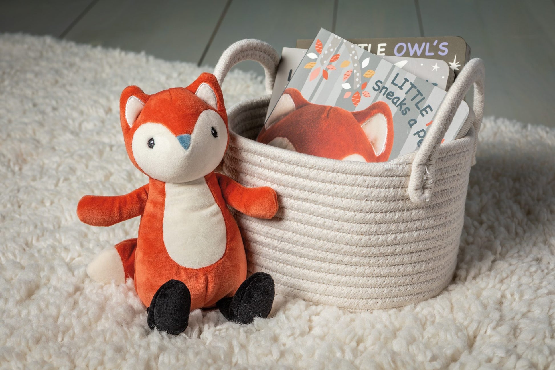 leika little fox soft toy displayed next to a basket of books on a white rug