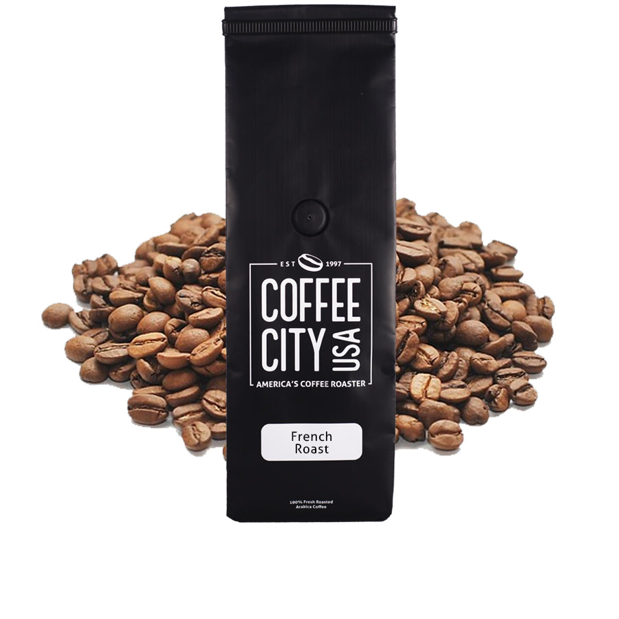 a black coffee bag filled with french roast coffee with a pile of coffee beans behind it on a white background