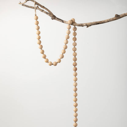 natural wood bead garland draped over a branch in front of a white background.