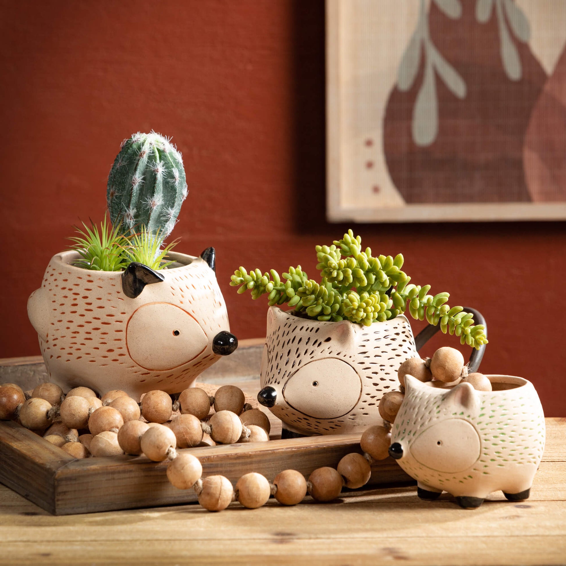 wooden tray with planters shape like hedgehogs filled with succulents and beaded garland draped across the tray.