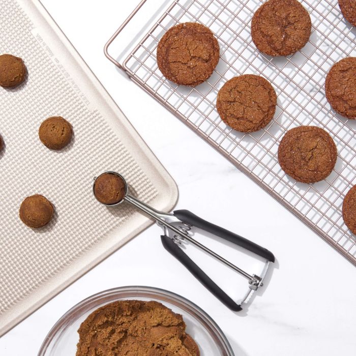 scoop on baking tray of cookie dough and cooling rack of baked cookies.