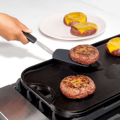 hand holding spatula removing burger from griddle.