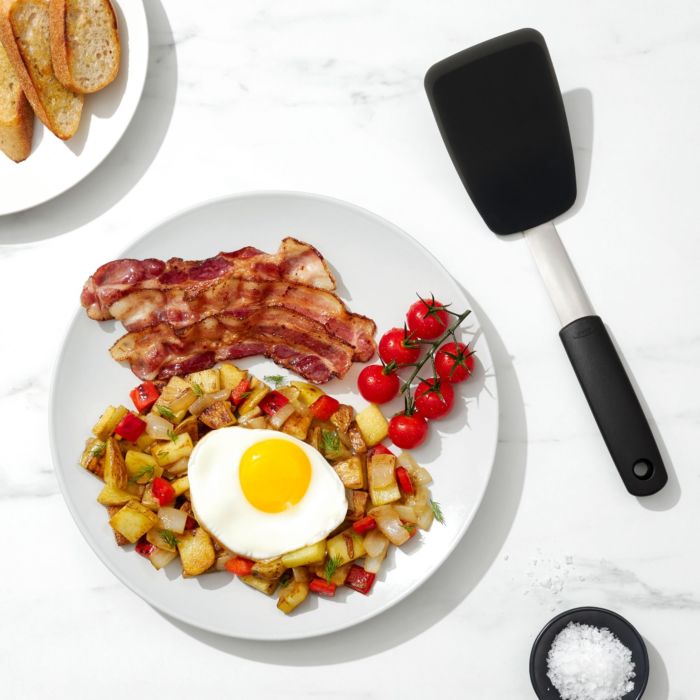 spatula set next to a plate of hashbrowns, bacon, and egg. 