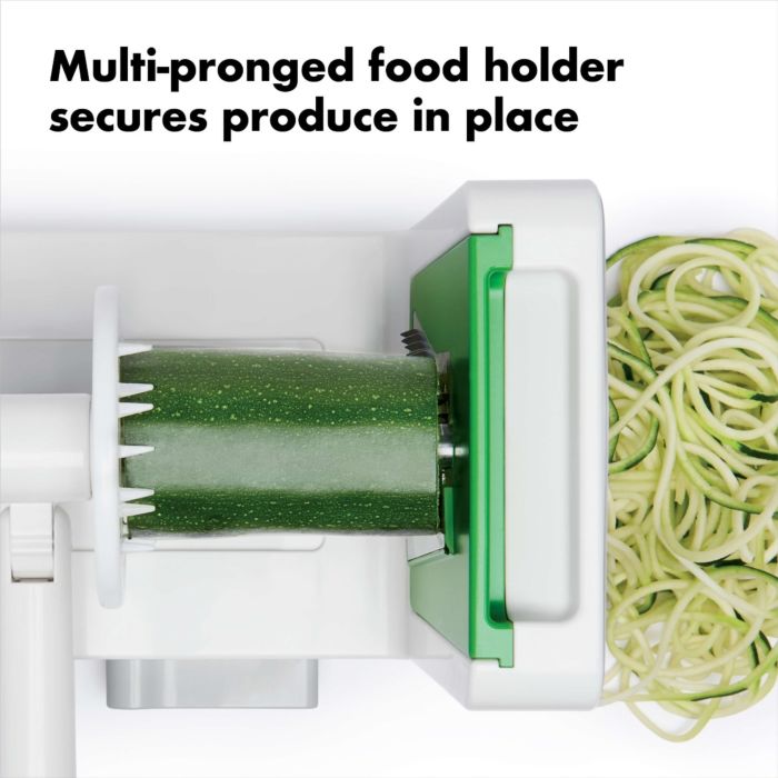 top view of spiralizer cutting zucchini with text "multi-pronged food holder secures produce in place".