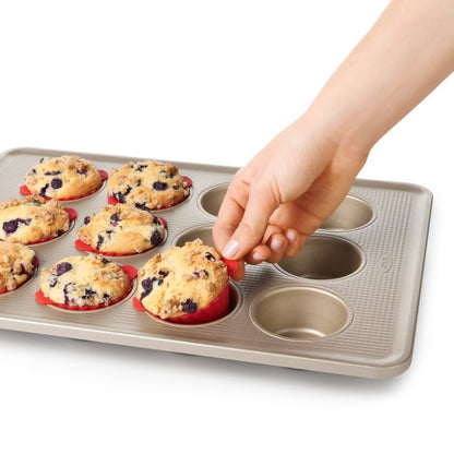 hand lifting baking cup out of muffin pan.