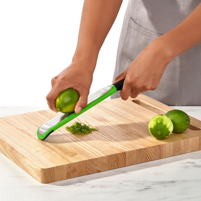hands zesting limes over cutting board.