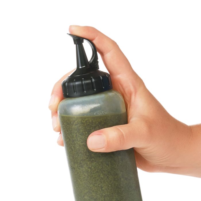 hand holding squeeze bottle filled with oil and herbs.