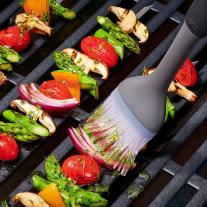 brush applying oil and herbs to veggies on grill.