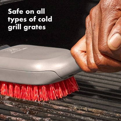 close-up of hand brushing grill with cleaning brush and text "safe on all types of cold grill grates".