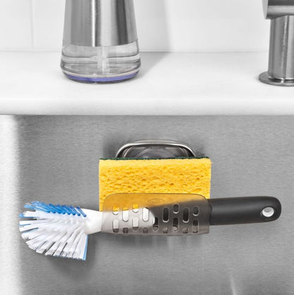 sponge holder attached to sink interior with sponge and scrub brush in it.