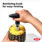 hand using pineapple slicer to slice pineapple with text "ratcheting knob for easy twisting".