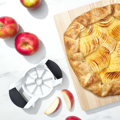 apple filled pastry on wood board with slicer and apples next to it.