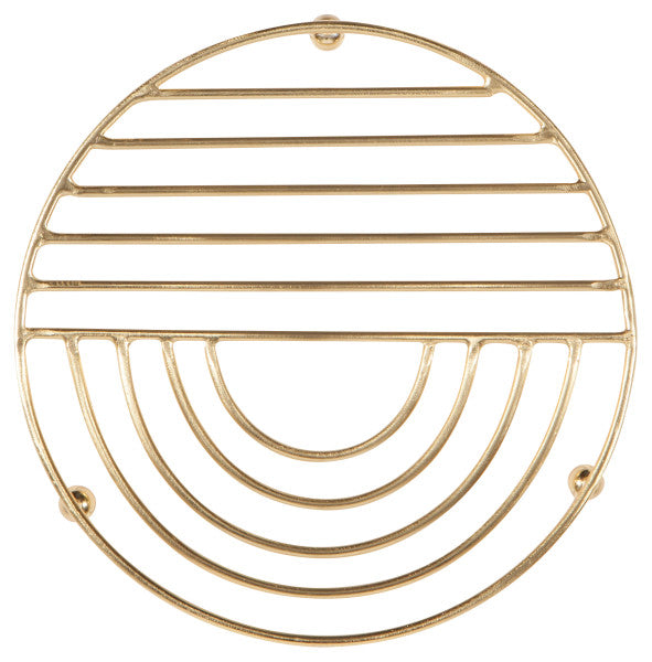 round gold trivet with straight lines on one half and curved lines on the other half.