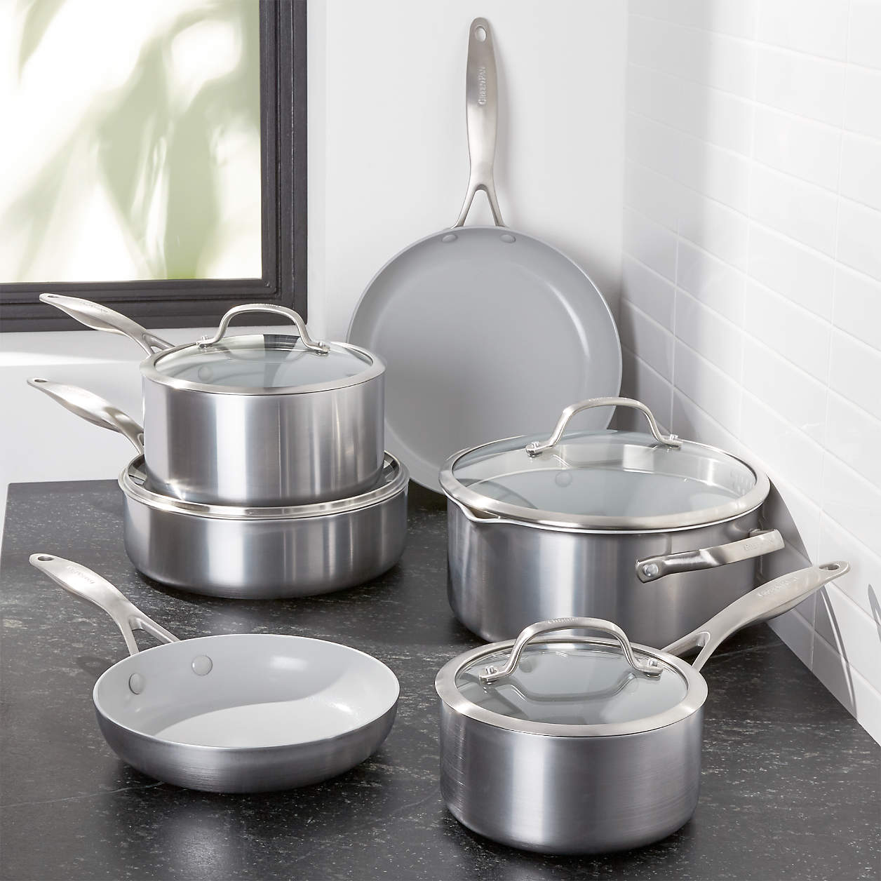 cookware stacked on grey countertop with white tile background.