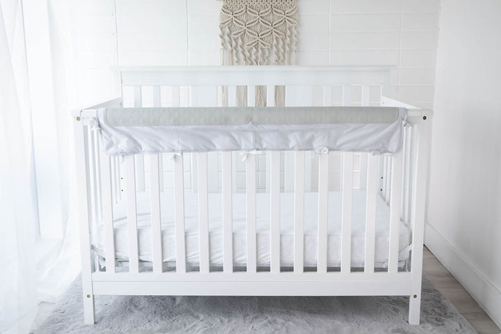 grey crib chomper displayed on a white crib in a child's room