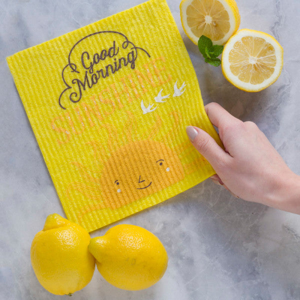 hand holding dishcloth over counter with lemons on it.