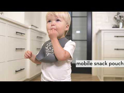 toddler wearing the bib and eating a snack in the kitchen